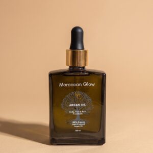 Braunglasflasche Moroccan Glow Arganöl 50 ml mit goldenem Ring und schwarzer Pipette vor beigem Hintergrund