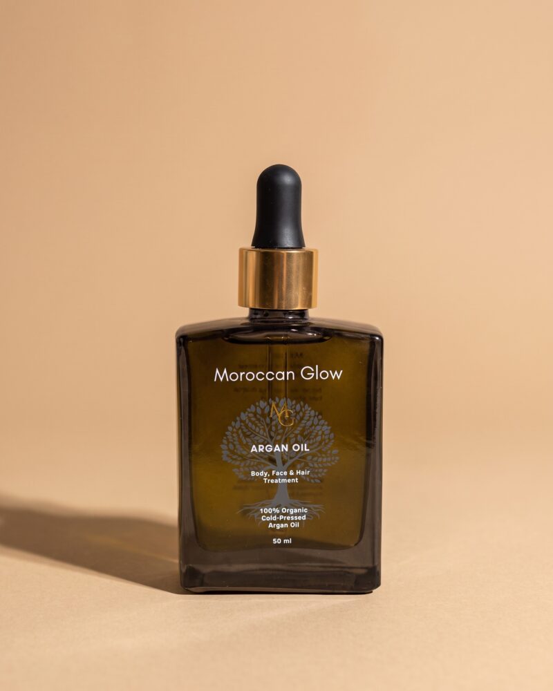 Braunglasflasche Moroccan Glow Arganöl 50 ml mit goldenem Ring und schwarzer Pipette vor beigem Hintergrund
